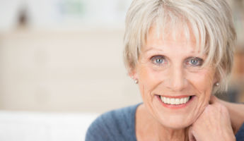 Close up facial portrait of a beautiful senior woman looking at the camera with a warm friendly smile and attentive expression